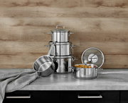 Topfset Astoria 5-tlg. aus Edelstahl, bestehend aus mehreren Töpfen und Deckeln, auf einer Küchenarbeitsplatte vor einer Holzrückwand, seitliche Perspektive.