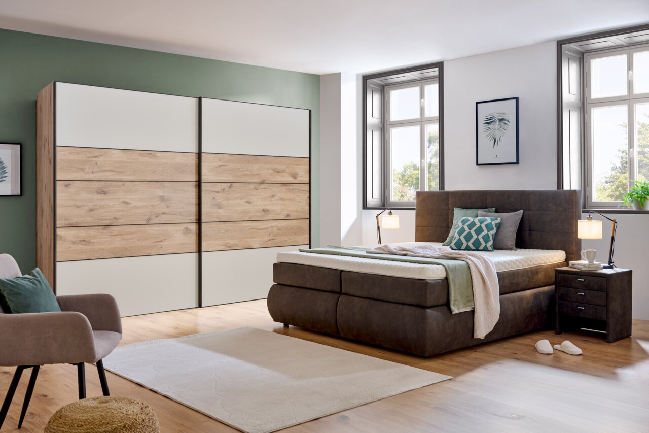 Moderner Schwebetürenschrank mit zwei Türen in Holzoptik und Weiß, seitliche Perspektive im stilvollen Schlafzimmer.