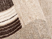 Nahaufnahme eines beigen Teppichs mit braunen Streifen, perspektivisch von der Seite aufgenommen.