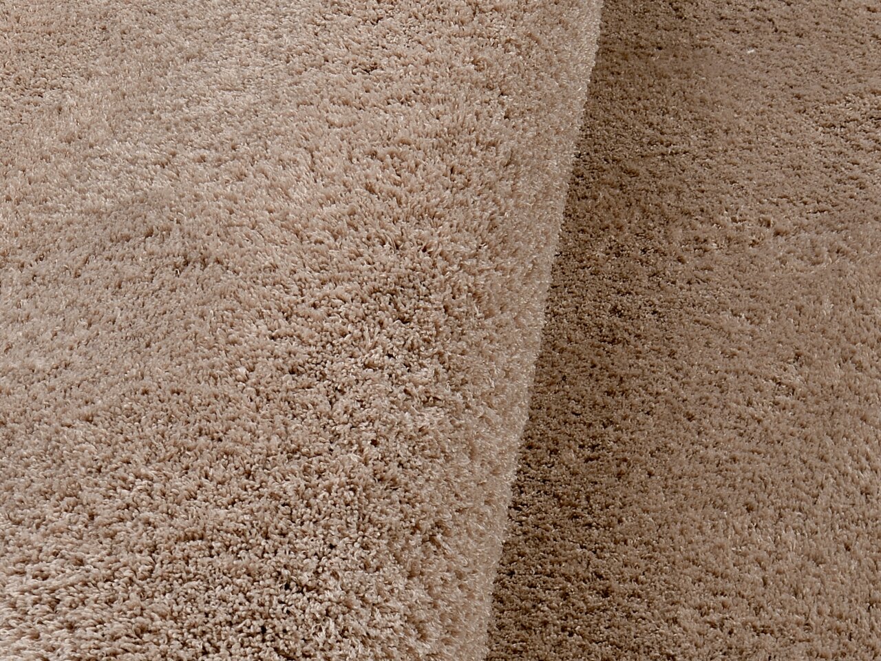 Nahaufnahme eines weichen, beigen Teppichs mit flauschiger Textur, perspektivisch von der Seite aufgenommen.
