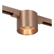 Koperkleurige cilindervormige railspot met warm licht, gemonteerd op een spanningsrail, close-up schuin van onderen