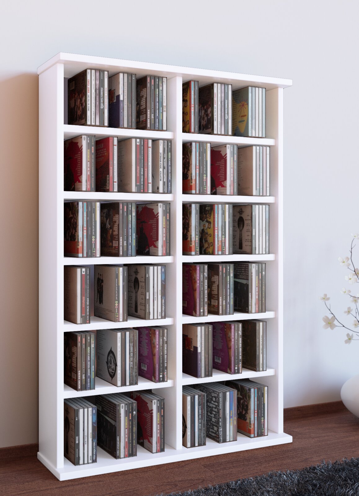 Weißes CD-/Medienregal aus Holz mit mehreren Fächern, gefüllt mit CDs, freistehend an einer Wand auf Holzboden, Perspektive: frontale Ansicht leicht von links