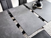 Moderner Esstisch mit grauer, erweiterbarer Tischplatte aus der Vogelperspektive, umgeben von grauen Stühlen.