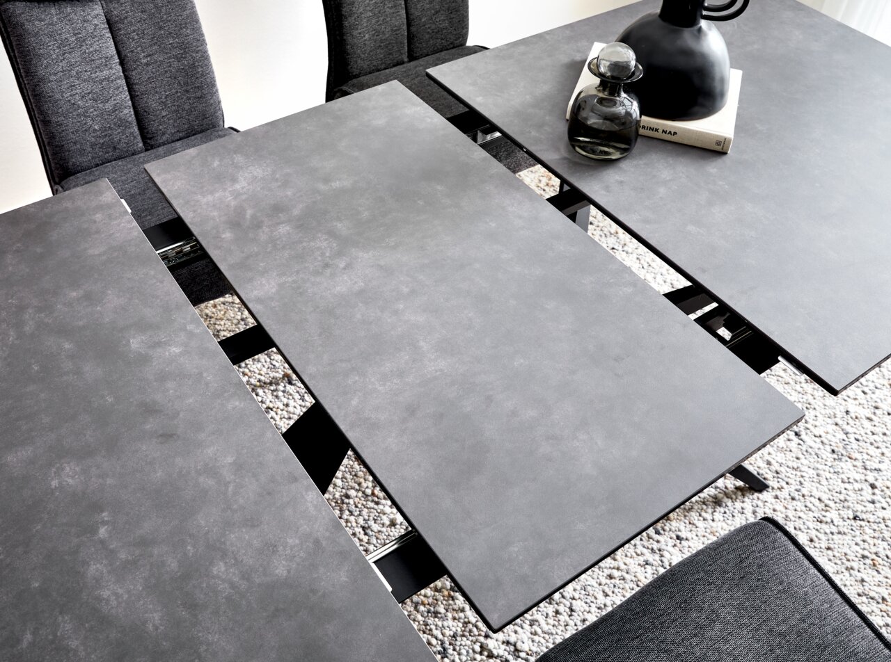 Moderner Esstisch mit grauer, erweiterbarer Tischplatte aus der Vogelperspektive, umgeben von grauen Stühlen.