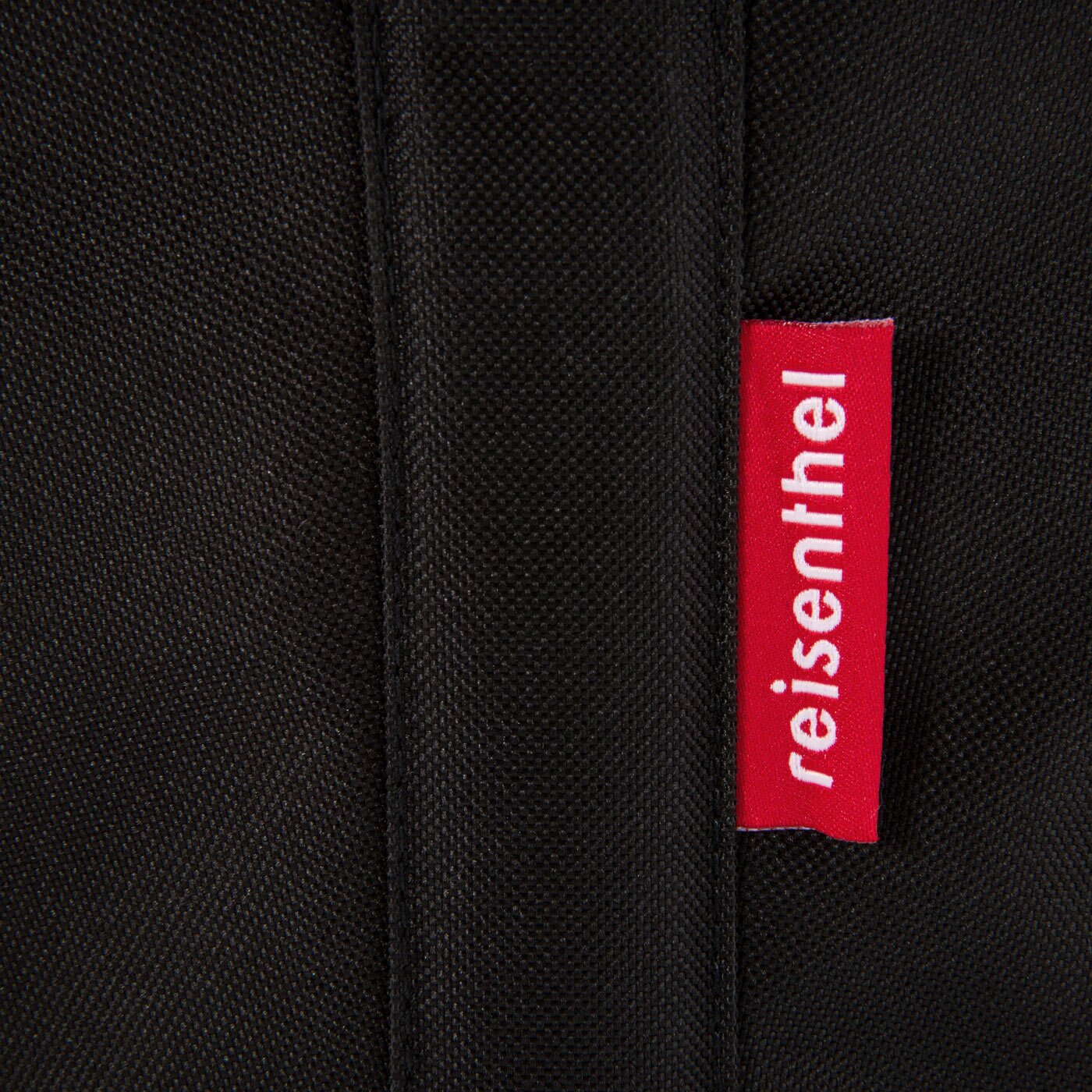 Close-up van een zwarte Carrybag met een rood 'reisenthel'-label.