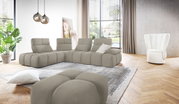 Modernes, hellgraues L-förmiges Modul-Ecksofa mit gepolsterten Rückenlehnen und Ottomane in einem hellen Wohnzimmer, aufgenommen in leichter Frontalansicht aus Augenhöhe.