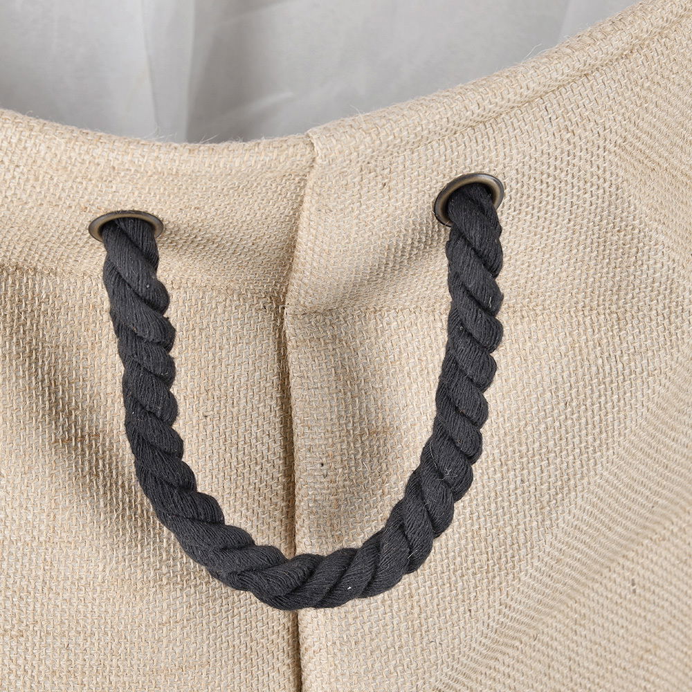 Nahaufnahme eines Wäschesammlers aus natürlicher Jute mit schwarzem Seilgriff, von oben betrachtet.