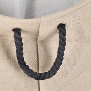 Nahaufnahme eines Wäschesammlers aus natürlicher Jute mit schwarzem Seilgriff, von oben betrachtet.