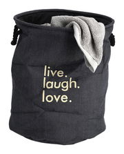 Wäschesammler 'Denim' in dunkler Jeansoptik mit dem Aufdruck 'live. laugh. love.' und einem Handtuch, aus der Vorderansicht fotografiert.