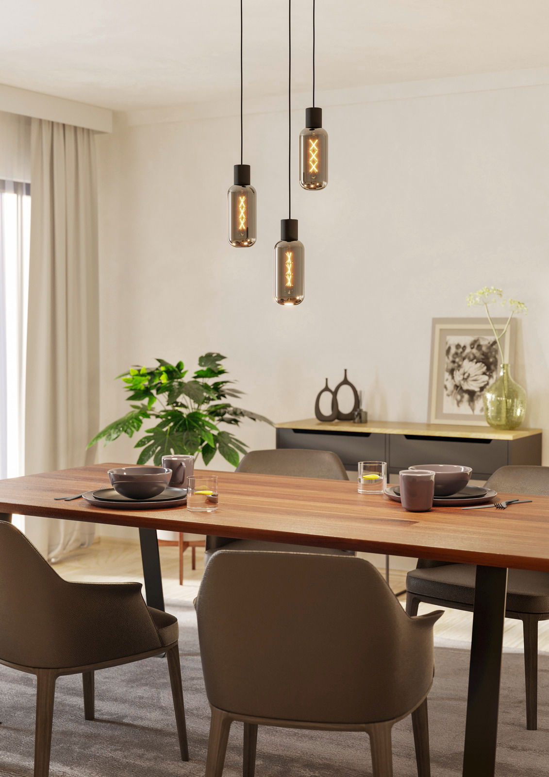 Moderne Pendelleuchte mit drei hängenden Glühbirnen über einem Esstisch, seitliche Perspektive.