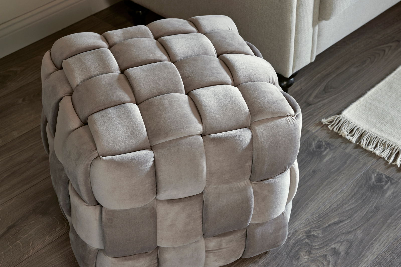 Grauer, gepolsterter Hocker mit quadratischem Muster, aus der Vogelperspektive fotografiert.