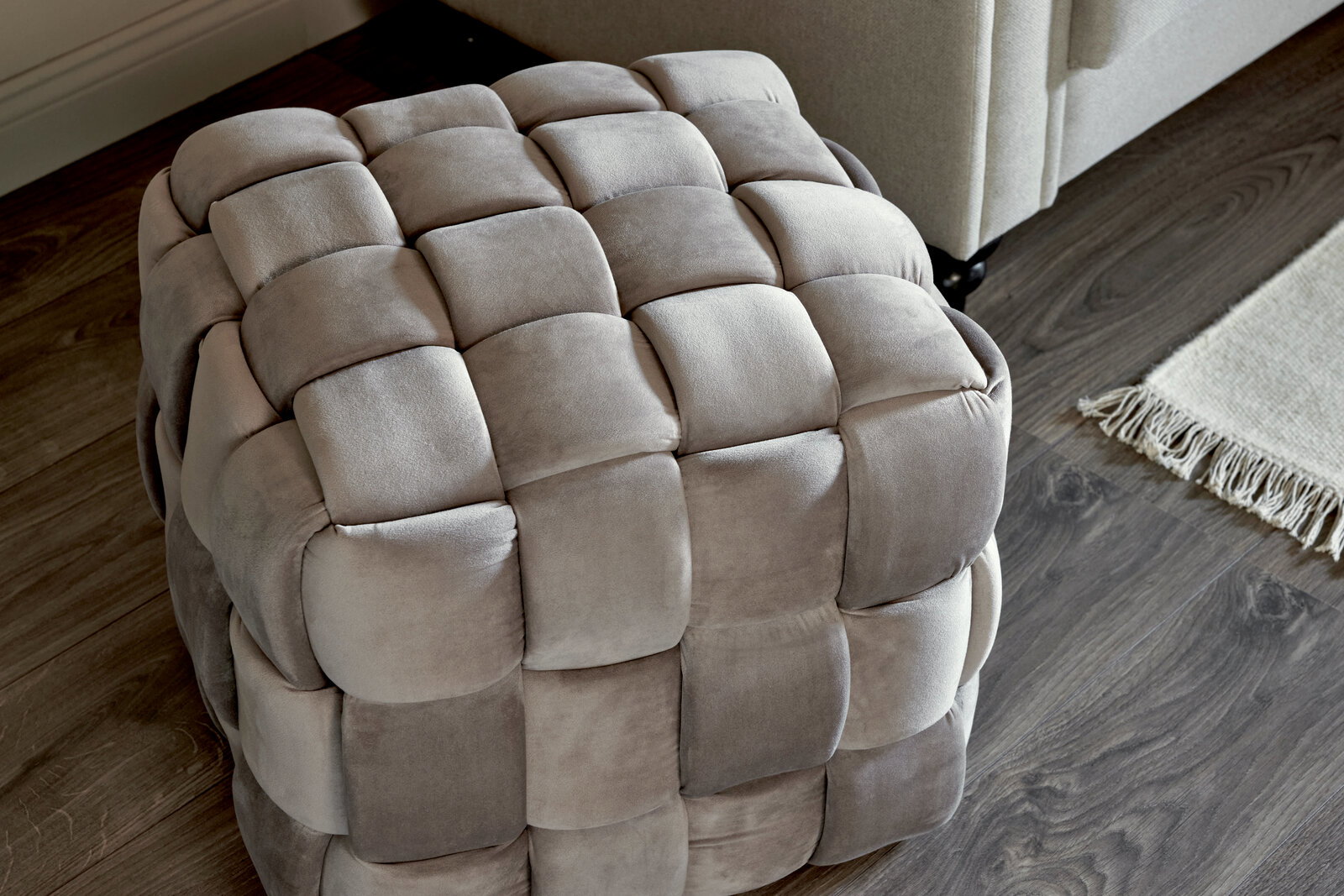 Grauer, gepolsterter Hocker mit quadratischem Muster, aus der Vogelperspektive fotografiert.