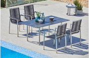 Moderne Gartenmöbelgarnitur mit Tisch und vier Stühlen aus Metall und Kunststoffgeflecht, seitliche Perspektive am Pool.