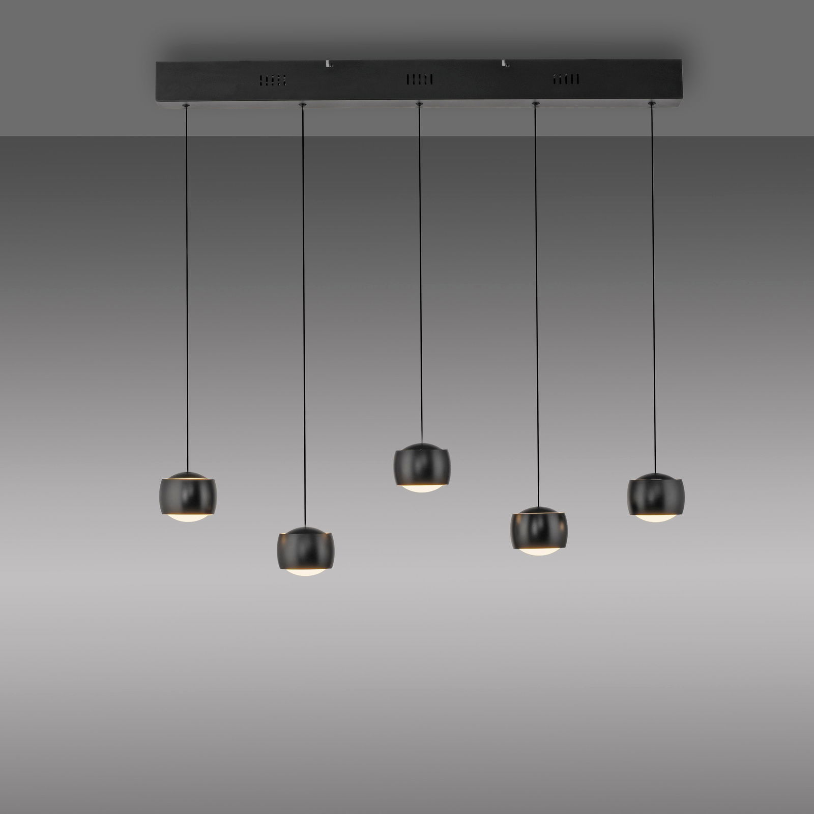 Moderne Pendelleuchte mit fünf schwarzen, kugelförmigen Lampenschirmen, die an dünnen Kabeln von einer rechteckigen Deckenhalterung hängen. Seitenansicht.