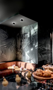 Zwei schwarze LED-Aufbauspots an der Decke eines stilvoll eingerichteten Cafés, Perspektive von unten.