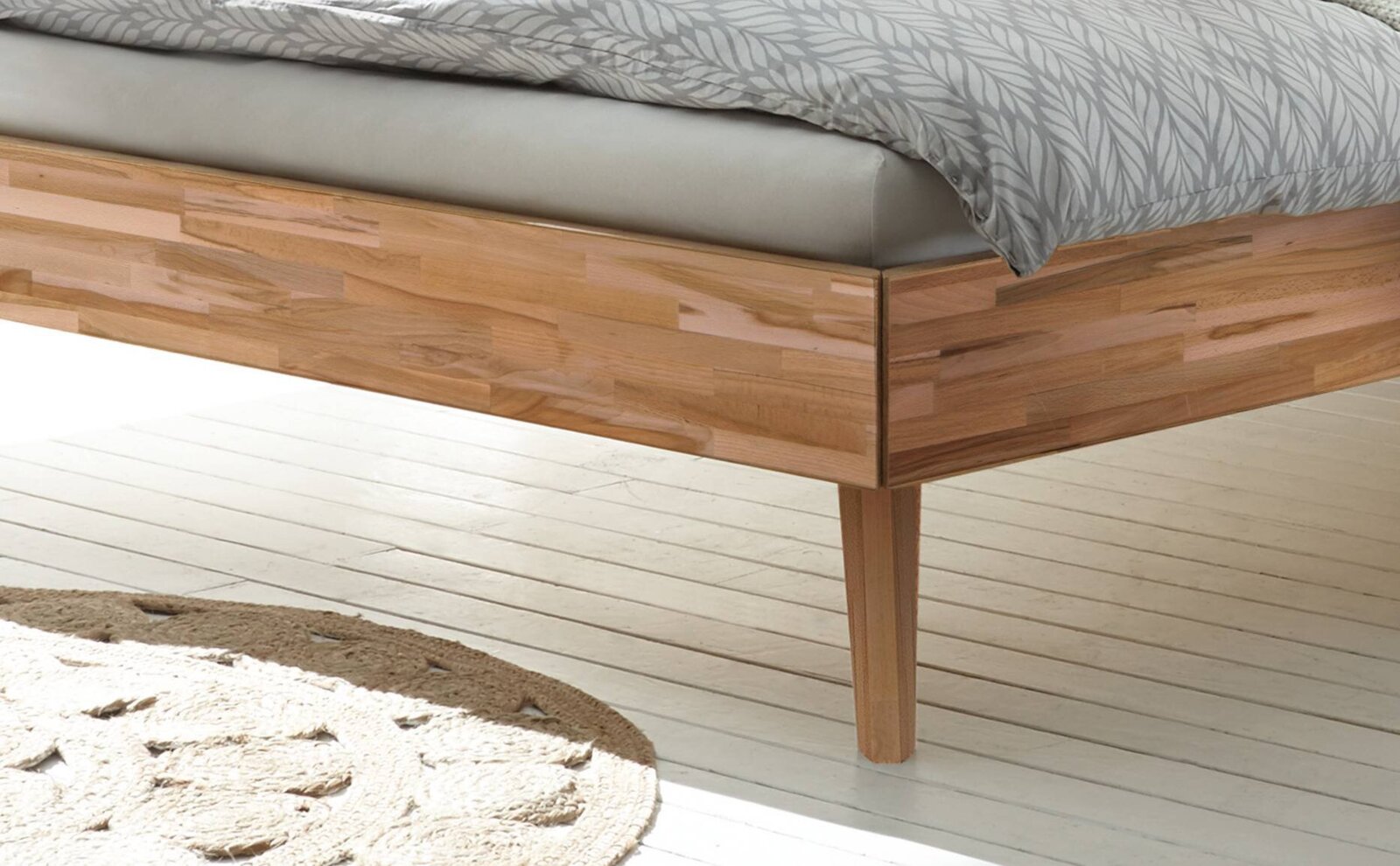 Close-up van een houten bedframe met natuurlijke nerf, gefotografeerd vanaf de zijkant.