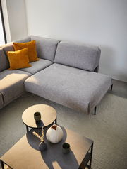 Graue Polsterrundecke mit zwei senfgelben Kissen, fotografiert aus der Vogelperspektive, neben zwei runden Beistelltischen mit Dekoration.