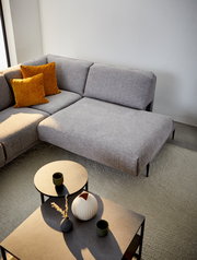 Graue Polsterrundecke mit zwei senfgelben Kissen, fotografiert aus der Vogelperspektive, neben zwei runden Beistelltischen mit Dekoration.