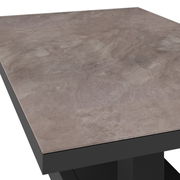 Nahaufnahme eines Gartentisches mit einer grauen, steinähnlichen Tischplatte und schwarzem Gestell, aus schräger Perspektive aufgenommen.