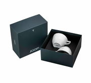Zwei weiße Tassen in einer eleganten schwarzen Geschenkbox von oben betrachtet, mit dem Logo 'JOOP!' auf der Unterseite der Tassen.
