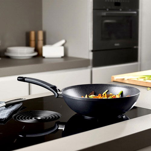 Fissler Wokpfanne Adamant 28cm Wokpfanne Adamant 28cm auf einem modernen Herd, seitliche Perspektive
