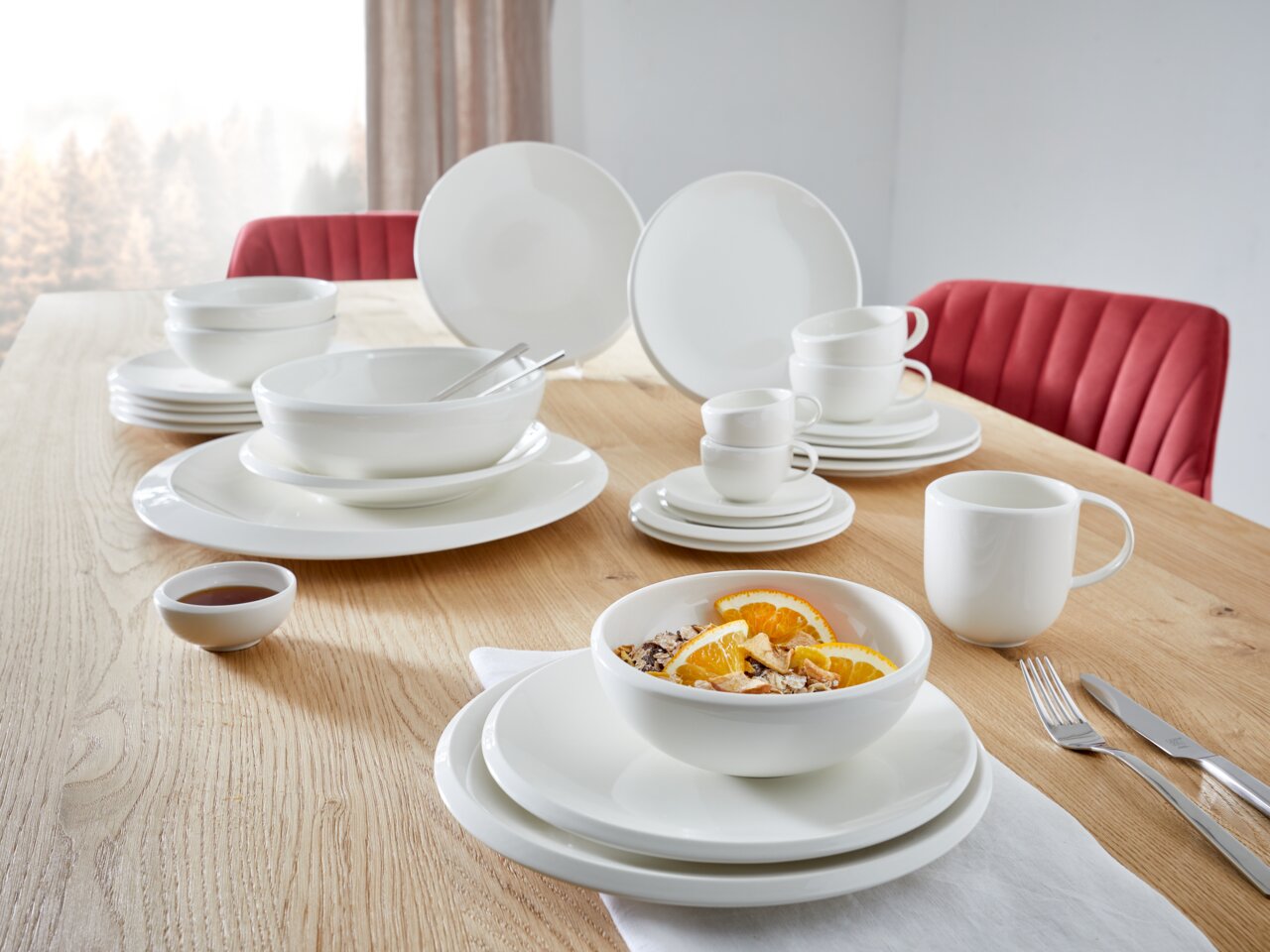 Frühstücks-Set, 6-tlg., auf einem Holztisch arrangiert, mit weißem Geschirr, Tassen und Schalen, seitliche Perspektive.