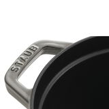 Nahaufnahme eines Griffs eines ovalen Bräters der Marke Staub, Perspektive von oben.