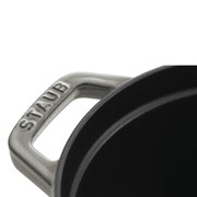 Close-up van een handvat van een ovale braadpan van het merk Staub, gezien van bovenaf.