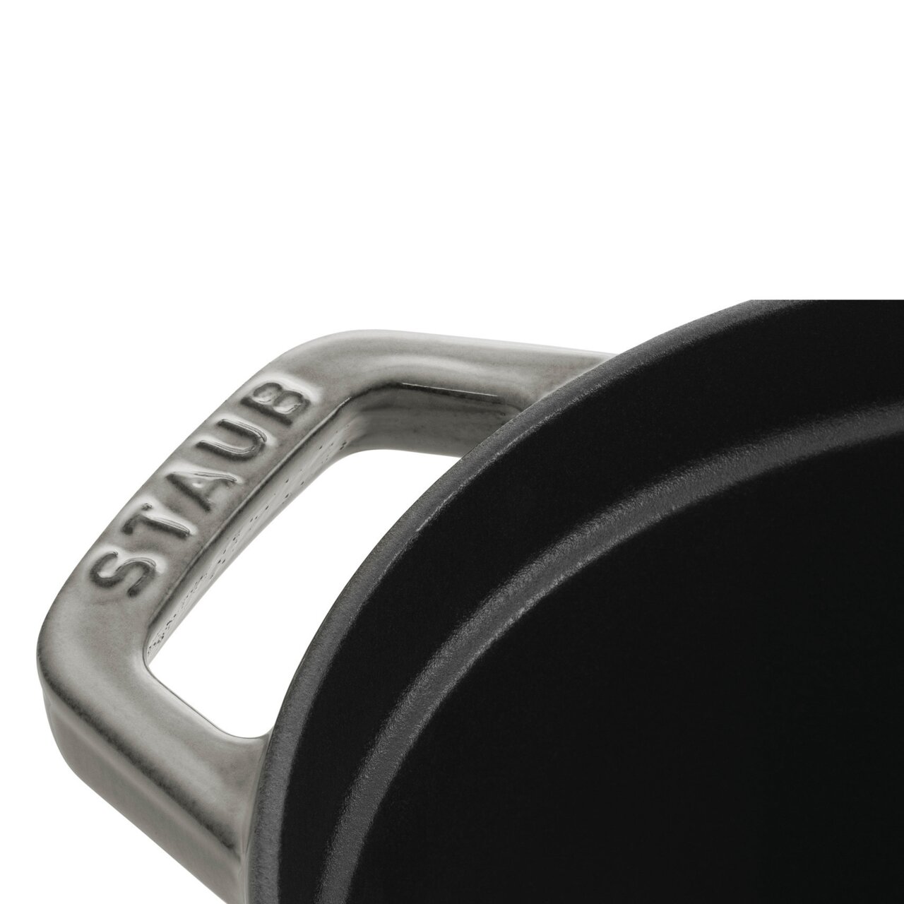 Close-up van een handvat van een ovale braadpan van het merk Staub, gezien van bovenaf.