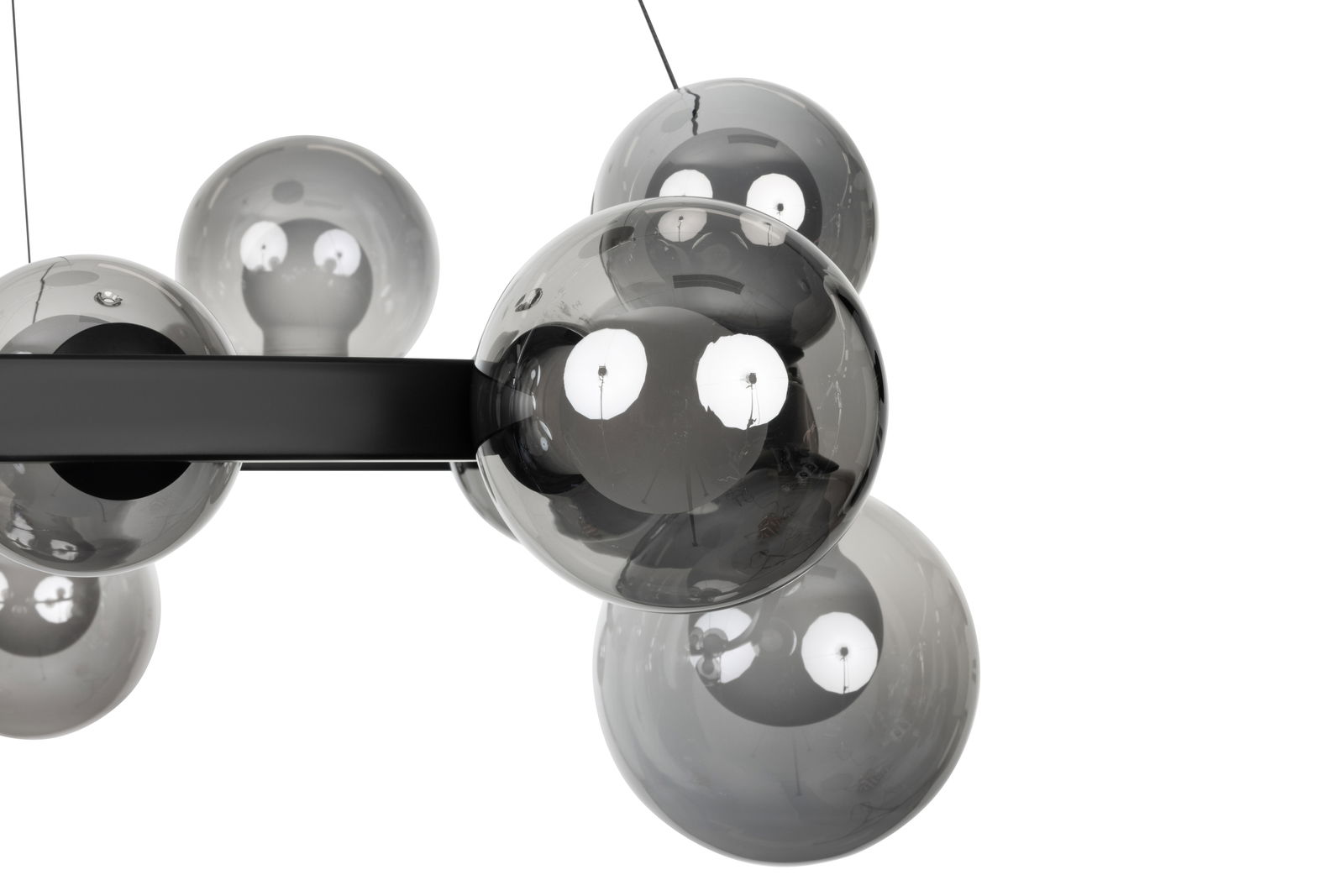 Nahaufnahme einer modernen LED-Hängeleuchte mit mehreren rauchgrauen Glaskugeln, seitliche Perspektive.