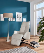 Moderner Fernsehsessel in hellem Leder, seitliche Perspektive, in einem stilvoll eingerichteten Wohnzimmer mit blauer Wand und großen Fenstern.