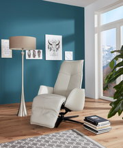 Moderner Fernsehsessel in hellem Leder, seitliche Perspektive, in einem stilvoll eingerichteten Wohnzimmer mit blauer Wand und großen Fenstern.