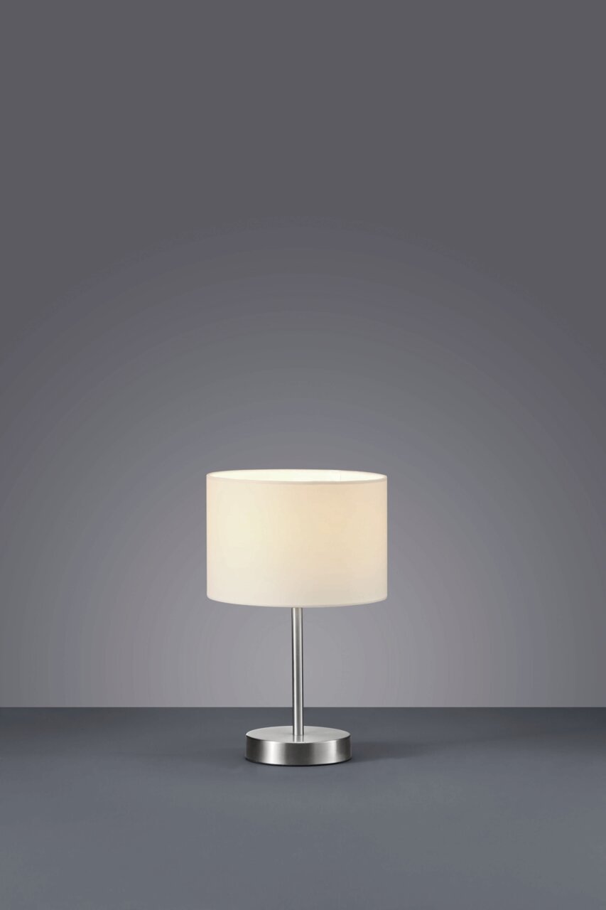 Tischlampe mit weißem Lampenschirm und silbernem Sockel, frontal fotografiert.
