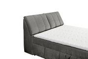 Seitliche Ansicht eines grauen Boxspringbetts mit gepolstertem Kopfteil und weißer Matratze.