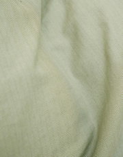 Nahaufnahme einer Bettwäsche mit Fischgrätenmuster in sanftem Grün.