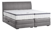 Boxspringbett in seitlicher Perspektive mit grauem Polster und weißer Matratze