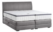 Boxspringbett in seitlicher Perspektive mit grauem Polster und weißer Matratze