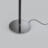 Nahaufnahme der Basis einer Stehleuchte OPPO mit glänzendem, runden Metallfuß und schwarzem Kabel auf grauem Hintergrund.