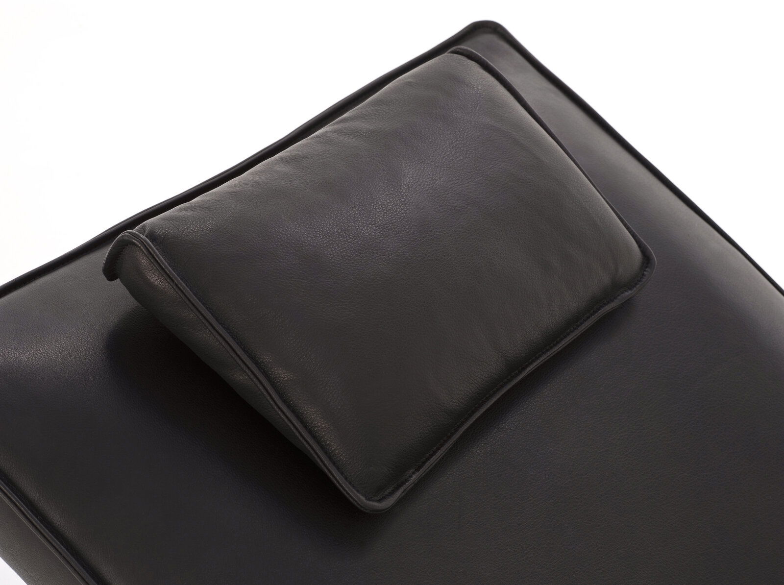 Nahaufnahme einer schwarzen Liege mit Kopfkissen, Perspektive von oben.