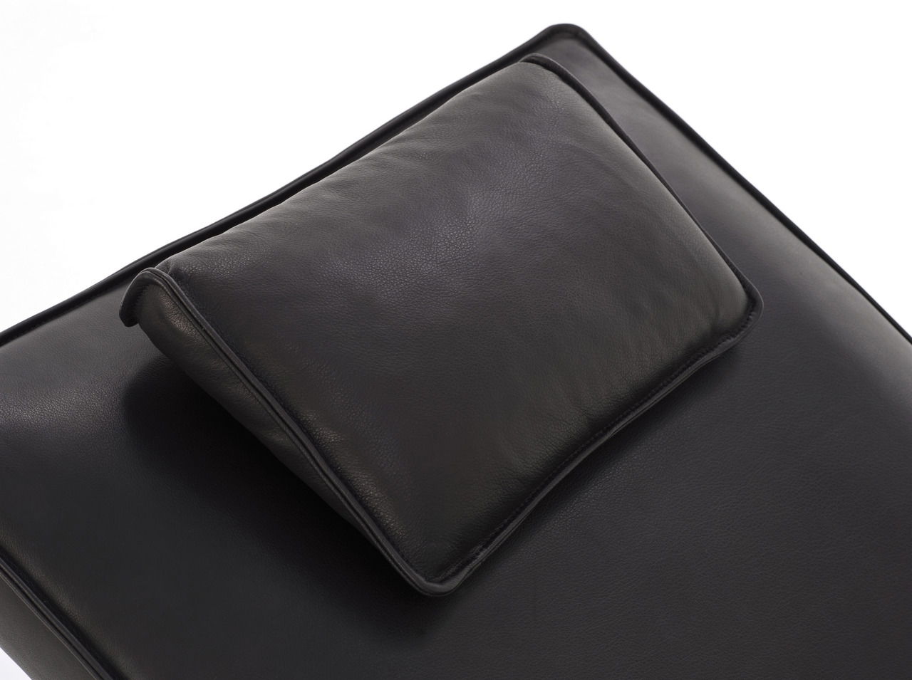 Nahaufnahme einer schwarzen Liege mit Kopfkissen, Perspektive von oben.