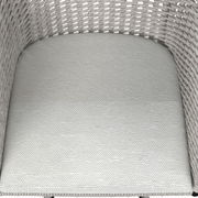 Nahaufnahme eines Armlehnstuhls mit geflochtenem Design und heller Polsterung, von oben betrachtet.