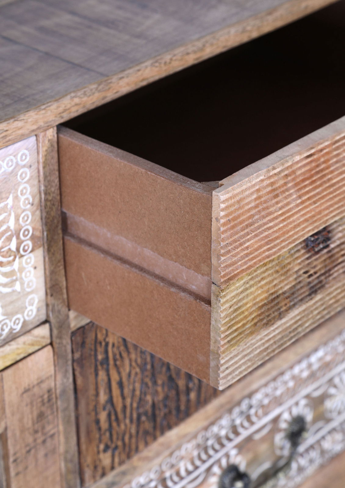 Landscape Sideboard PUNO Nahaufnahme einer geöffneten Schublade eines rustikalen Möbelstücks mit dekorativen Schnitzereien und Holzmaserung, Perspektive von schräg oben.