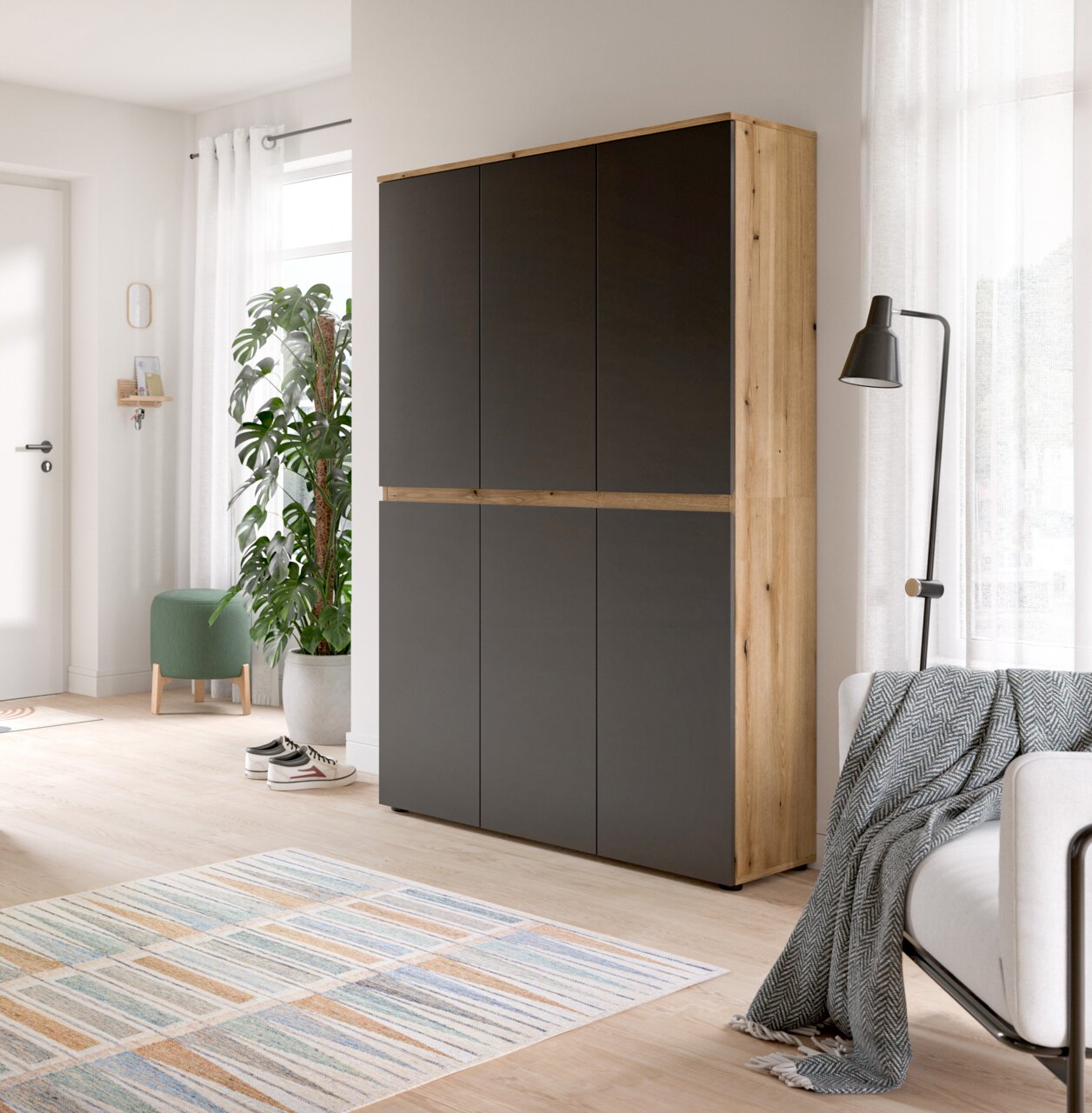 Hoher, moderner Schrank mit mattschwarzen Fronten und hellem Holzrahmen im Wohnzimmer, frontale Ansicht mit leichter Perspektive von rechts.