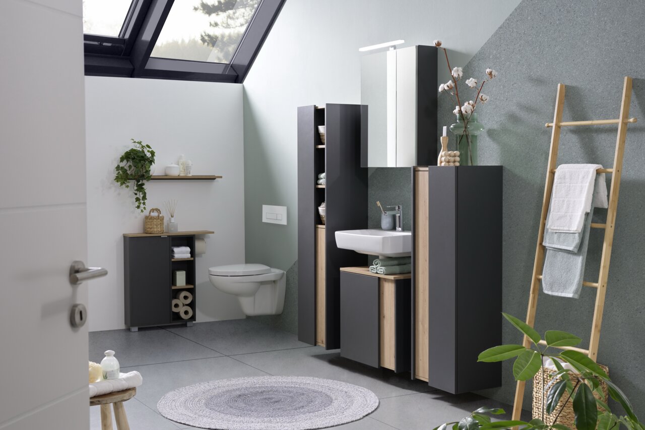 Moderner Spiegelschrank in einem stilvollen Badezimmer mit Dachfenster, grauen Wänden und Holzdetails, aus der Perspektive von der Tür aus gesehen.