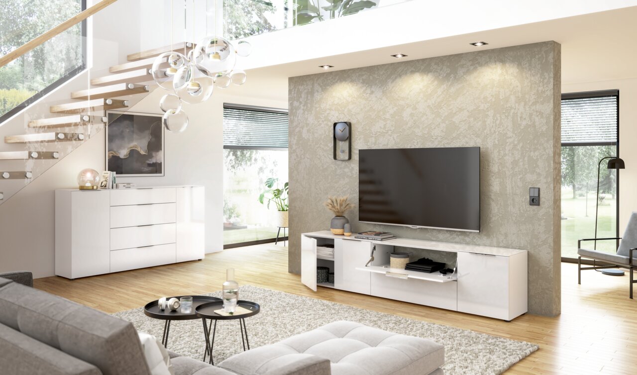 Modernes Wohnzimmer mit weißem TV-Lowboard und großem Flachbildfernseher an der Wand, seitliche Perspektive.