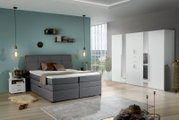 Moderner weißer Drehtürenschrank mit sechs Türen in einem stilvoll eingerichteten Schlafzimmer, seitliche Perspektive.