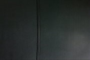 Nahaufnahme einer schwarzen, strukturierten Polsteroberfläche mit einer zentralen Naht.