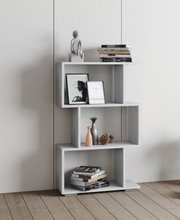 Modernes weißes Stufenregal mit asymmetrischen offenen Fächern, dekoriert mit Büchern, Bilderrahmen, Vasen und Zapfen, freistehend vor heller Wand; Perspektive: Frontalansicht auf Augenhöhe.