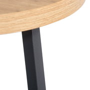 Nahaufnahme eines Beistelltisches mit runder Holzplatte und schwarzem Metallbein, seitliche Perspektive