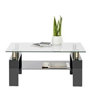 Moderner Couchtisch mit Glasplatte und schwarzem Gestell, dekoriert mit einer Pflanze und Büchern, seitliche Perspektive.